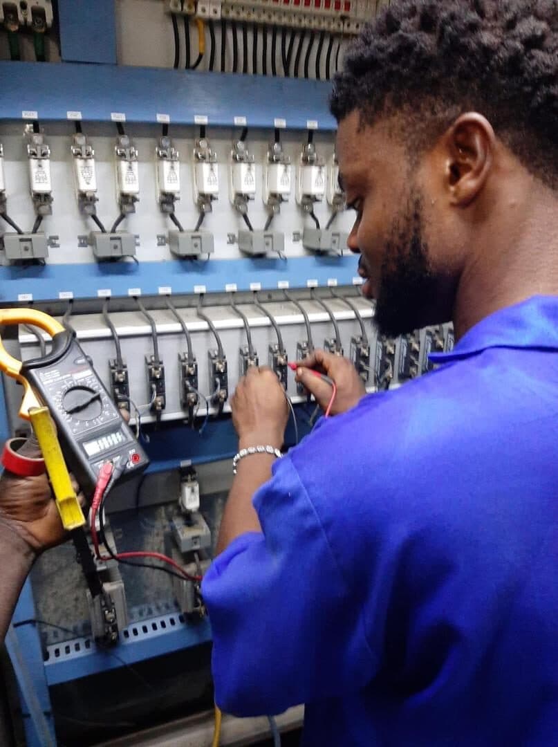 Technician using a clamp meter to test a relay control panel